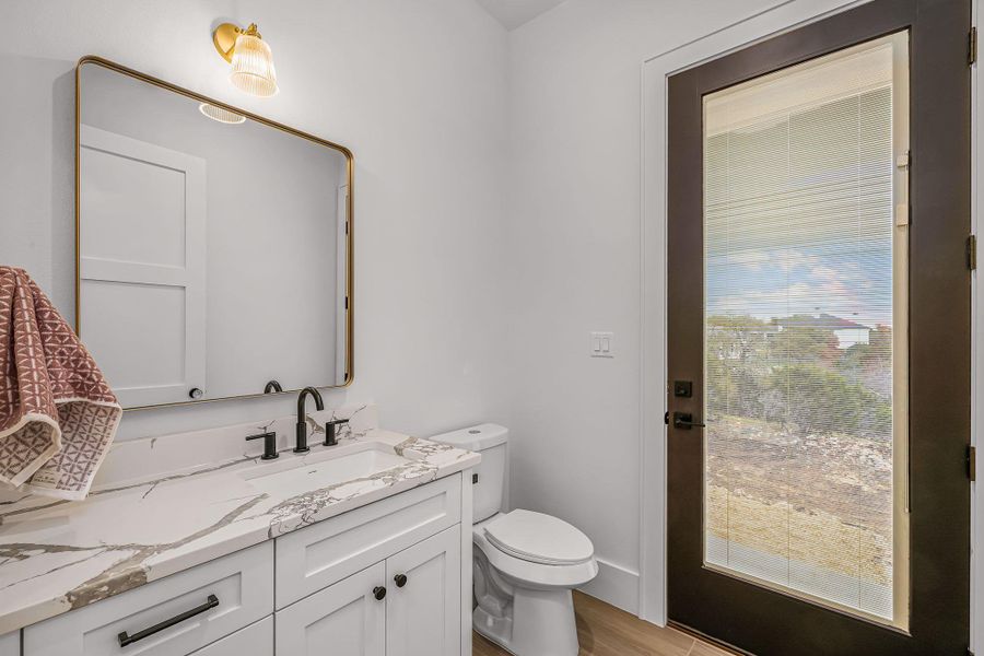 Half bathroom featuring toilet, wood finished floors, and vanity