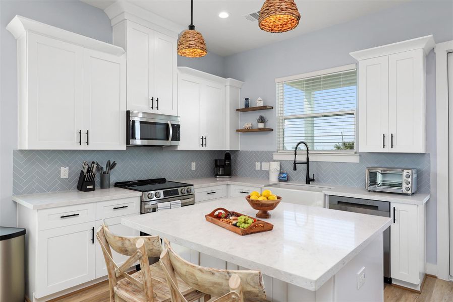 The modern kitchen is both functional and stylish, showcasing sleek granite countertops, stainless steel appliances, and a large island with seating for casual dining or conversation.