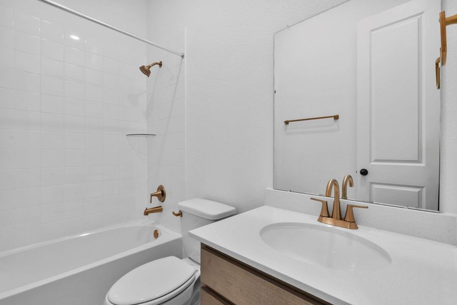 Modern third bath featuring the AW Collection Laguna with stained cabinetry, light countertops with brass fixtures and a convenient shower/tub combo.