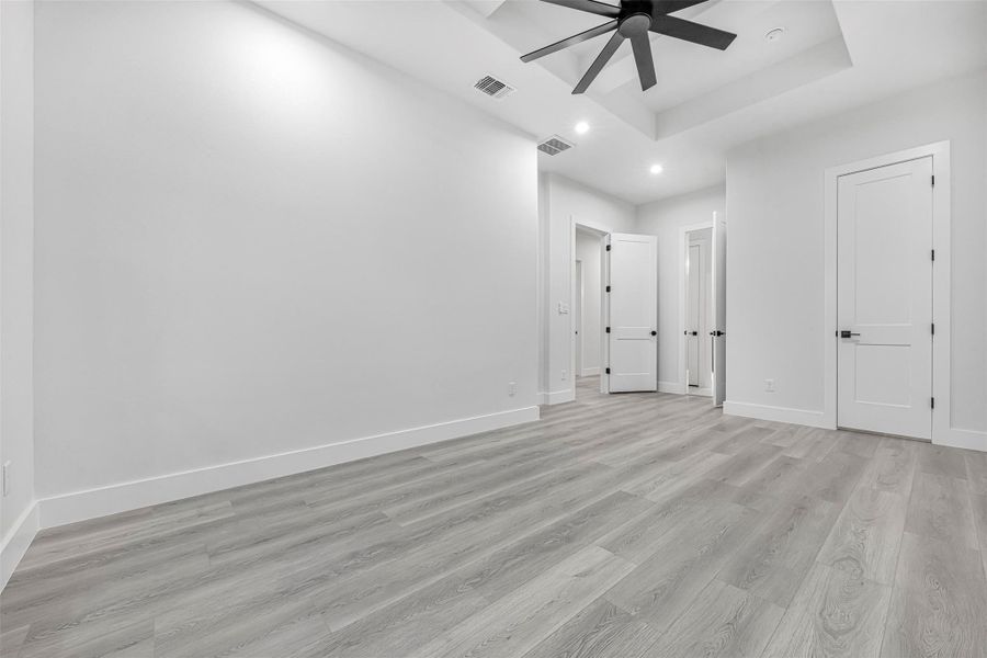Unfurnished bedroom with recessed lighting, light wood-style flooring, baseboards, tray ceiling, and ceiling fan. Unfurnished bedroom with recessed lighting, light wood-style flooring, baseboards, tray ceiling, and ceiling fan.