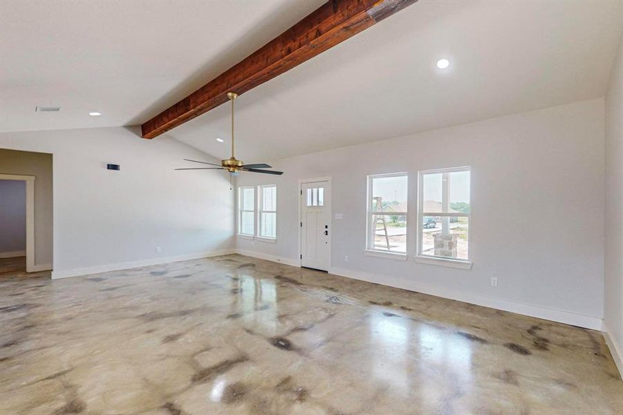 Unfurnished living room with lofted ceiling with beams and ceiling fan