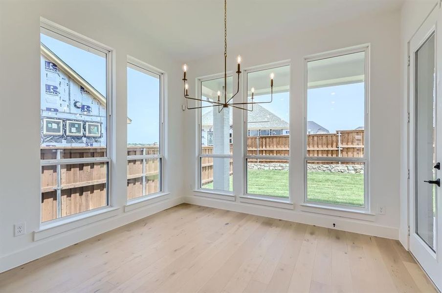 Unfurnished dining area featuring light wood-type flooring, plenty of natural light, and an inviting chandelier