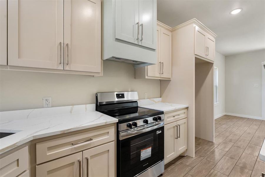 Kitchen featuring light-toned cabinetry, white countertops, and a stainless steel range with a matching range hood Kitchen featuring light-toned cabinetry, white countertops, and a stainless steel range with a matching range hood
