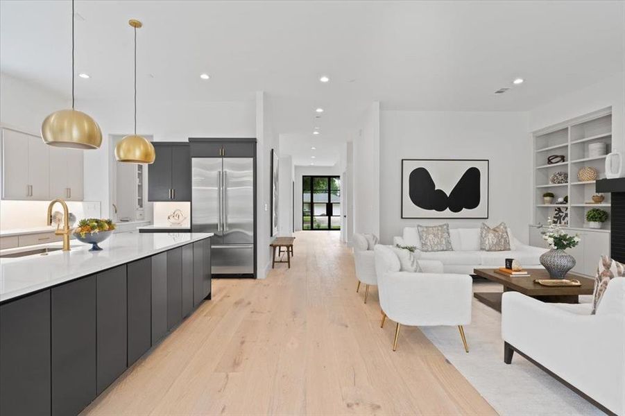 Kitchen featuring stainless steel built in fridge, pendant lighting, sink, and light wood-type flooring