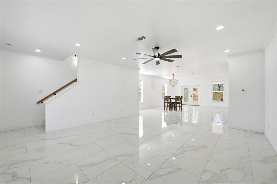 Living room with light marble finish floors, recessed lighting, ornamental molding, and a ceiling fan Living room with light marble finish floors, recessed lighting, ornamental molding, and a ceiling fan