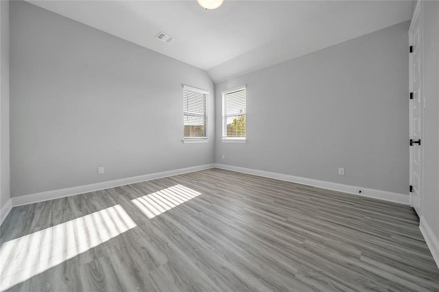 Empty room featuring lofted ceiling and light wood finished floors Empty room featuring lofted ceiling and light wood finished floors