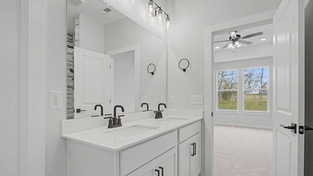 Bathroom with dual sink vanity, quartz countertop, and tiled floors and shower