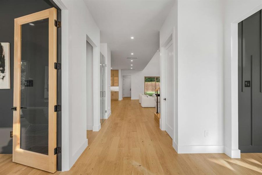 Corridor featuring light wood finished floors, elevator, and recessed lighting