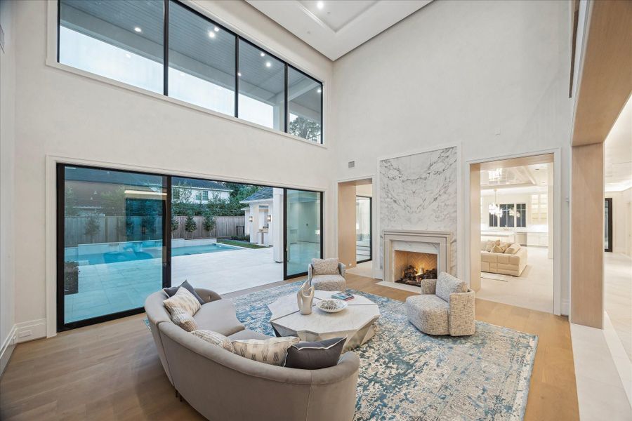 Flooded with light and framed by pool views, the 18x22 living room boasts a soaring ceiling and an elegant custom coffered tray.