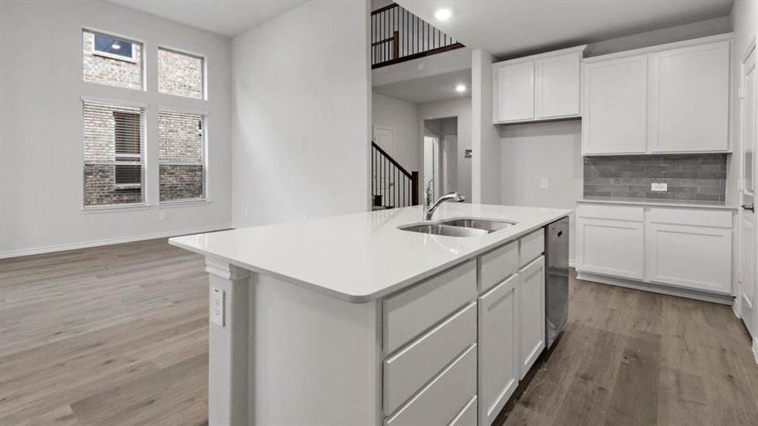 Kitchen with white cabinets, a kitchen island with sink, light wood-type flooring, light stone countertops, and recessed lighting Kitchen with white cabinets, a kitchen island with sink, light wood-type flooring, light stone countertops, and recessed lighting