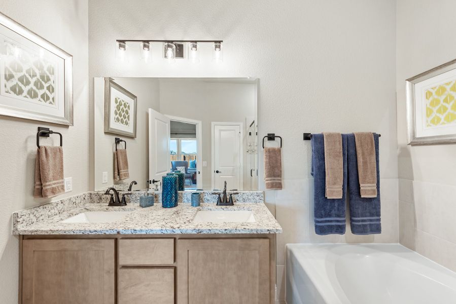 Bathroom with double sink vanity, granite countertop, wood cabinets, and soaking tub beside towel rack Bathroom with double sink vanity, granite countertop, wood cabinets, and soaking tub beside towel rack
