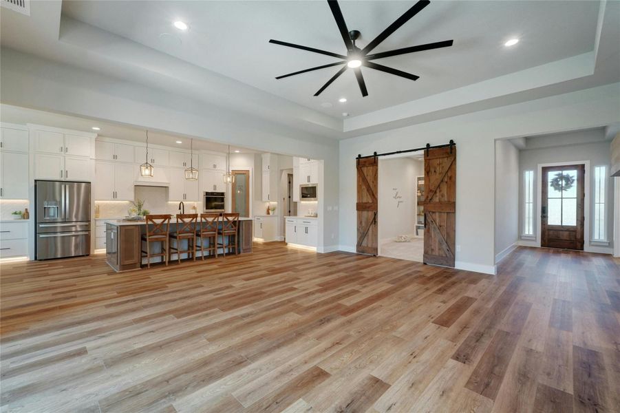 Spacious open-concept living area featuring wood-finish flooring, a contemporary ceiling fan, and recessed lighting