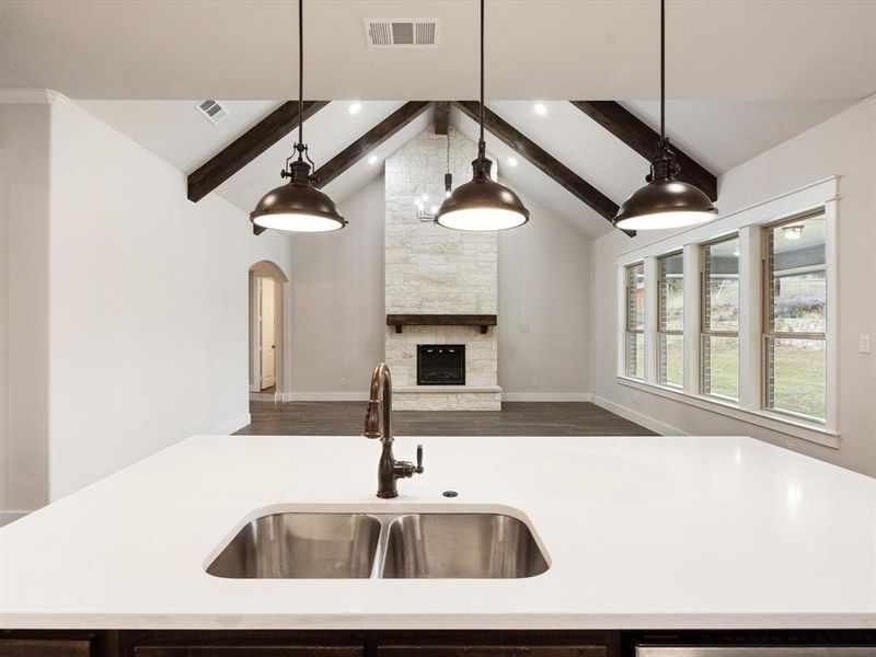 Kitchen featuring a center island with sink, hanging light fixtures, and a fireplace