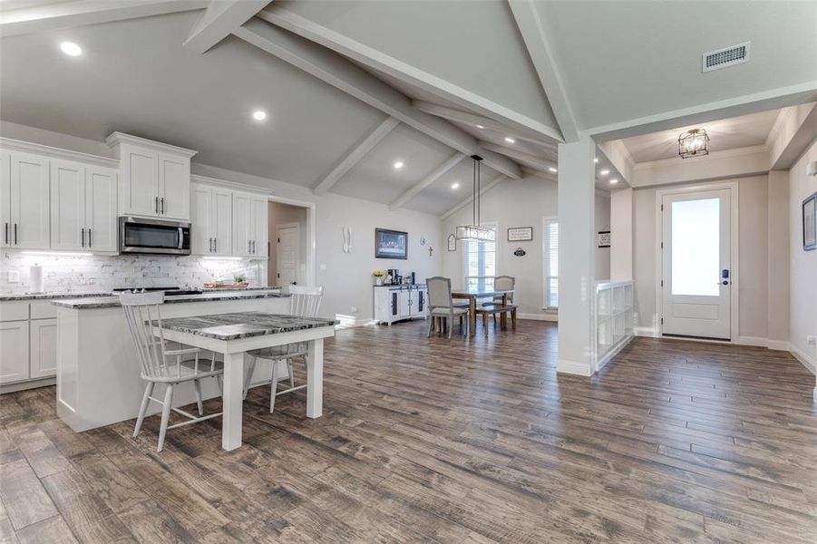 Kitchen featuring beam ceiling, white cabinets, tasteful backsplash, recessed lighting, and stainless steel microwave