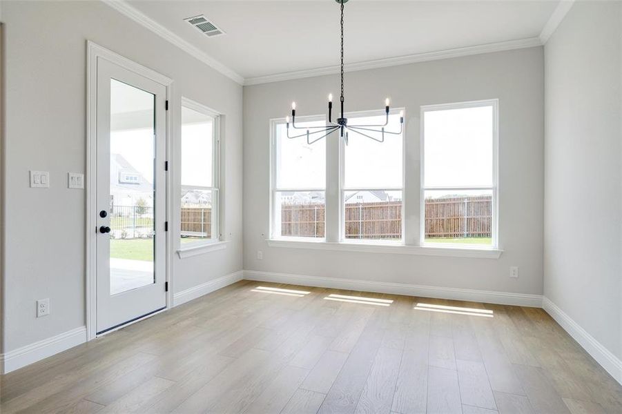 Unfurnished dining area with crown molding, light wood-type flooring, and a chandelier