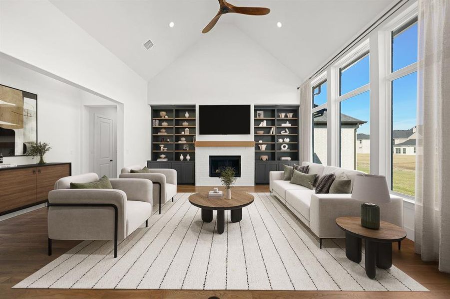 Living room featuring a fireplace, high vaulted ceiling, wood finished floors, and ceiling fan Living room featuring a fireplace, high vaulted ceiling, wood finished floors, and ceiling fan