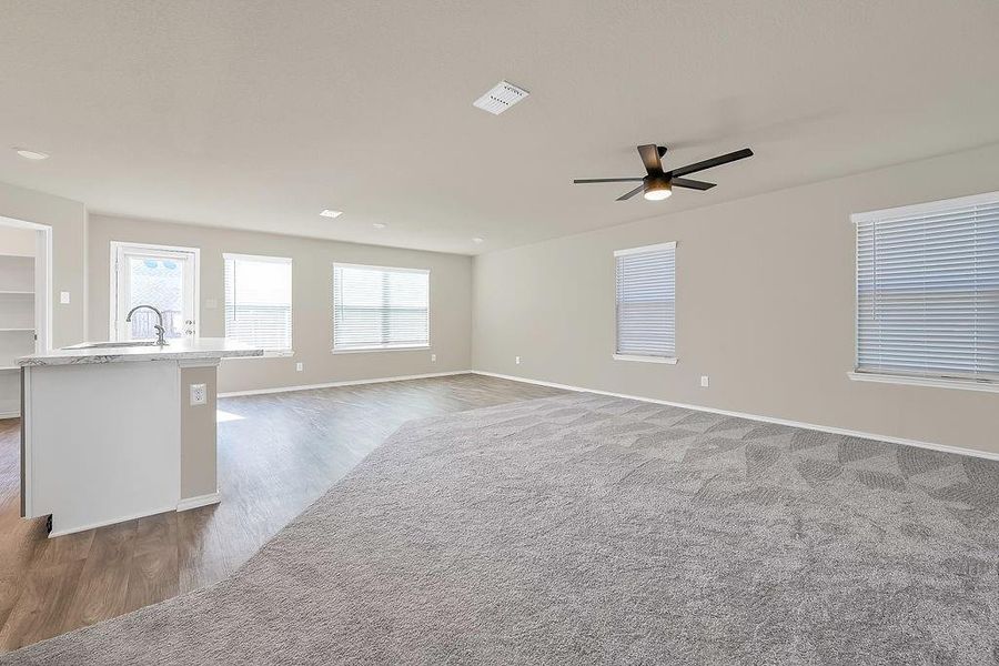 Unfurnished living room featuring a healthy amount of sunlight, ceiling fan, and dark hardwood / wood-style floors