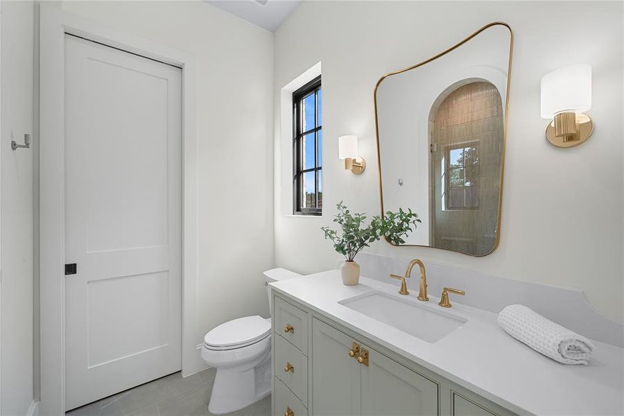 Bathroom featuring a light green vanity with brass hardware, a white countertop, and a built-in sink