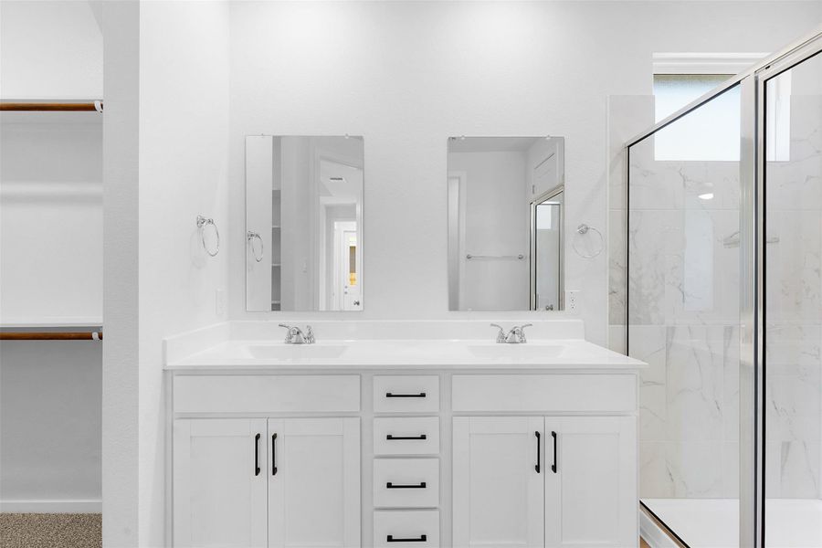 Bathroom featuring a marble finish shower, double vanity, and a walk in closet Bathroom featuring a marble finish shower, double vanity, and a walk in closet