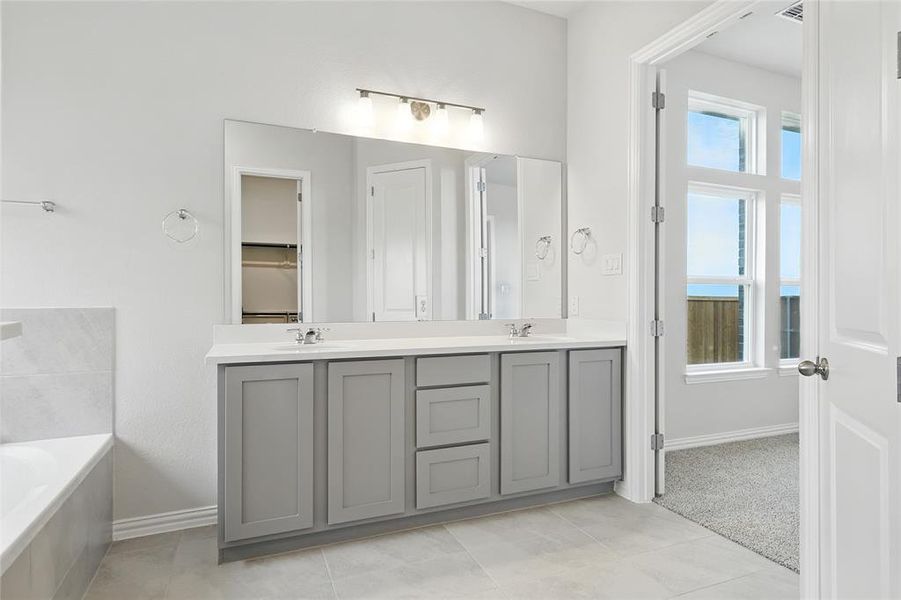 Bathroom featuring a bath, double vanity, light tile patterned flooring, and a closet Bathroom featuring a bath, double vanity, light tile patterned flooring, and a closet
