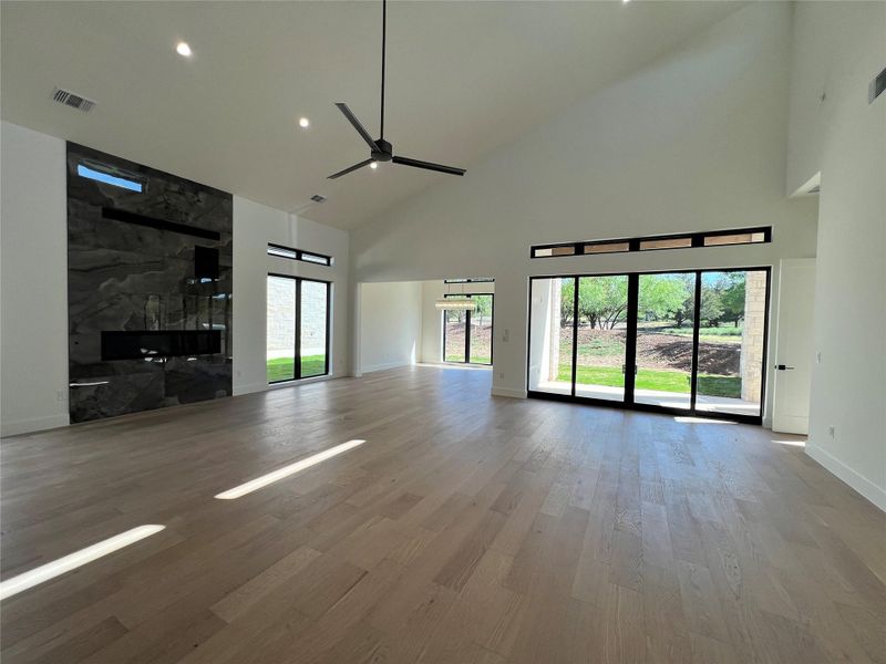 Unfurnished living room with light wood-style flooring, a ceiling fan, vaulted ceiling, and recessed lighting