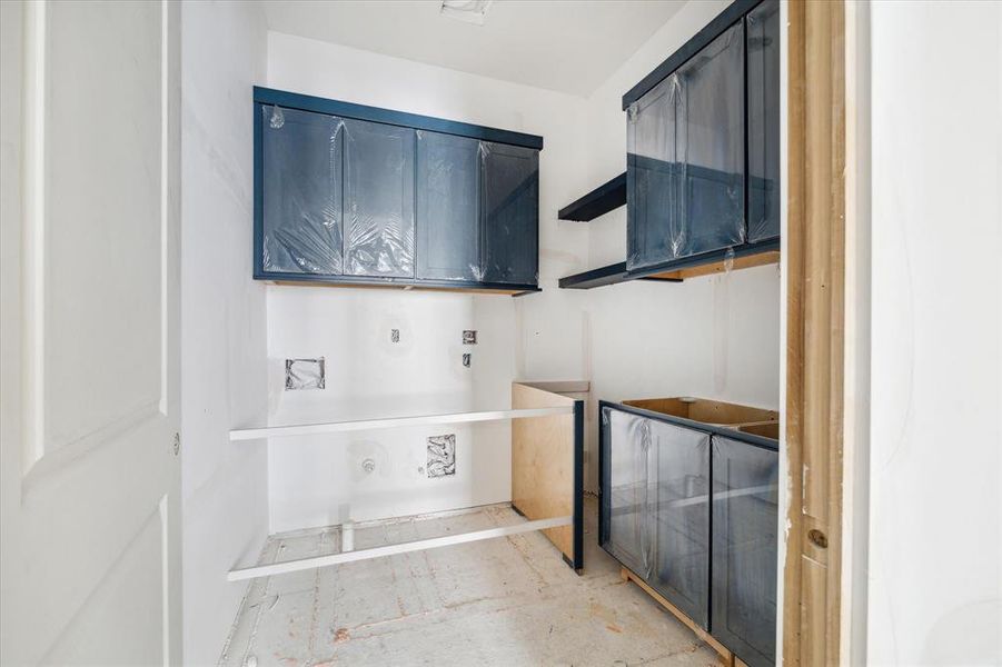 Within the spacious utility room, there is dedicated built-in space for a side-by-side washer and dryer. Furthermore, the room provides abundant storage for laundry essentials like detergent, along with convenient shelving and a sink for added functionality.