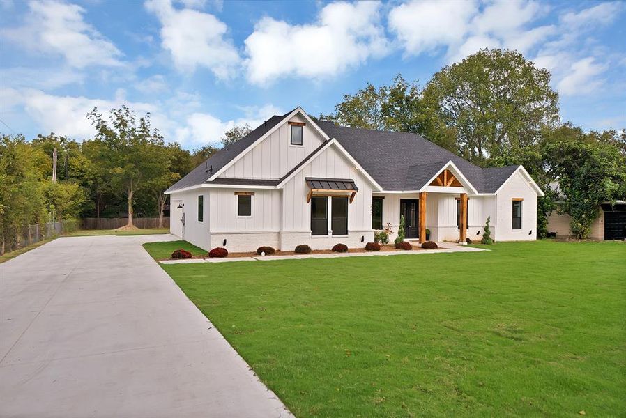 Modern farmhouse with board and batten siding, a shingled roof, covered porch, concrete driveway, and a standing seam roof Modern farmhouse with board and batten siding, a shingled roof, covered porch, concrete driveway, and a standing seam roof