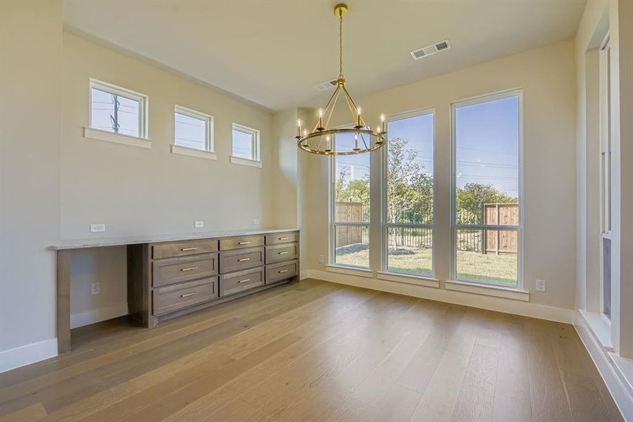 Unfurnished dining area featuring light wood-type flooring and a chandelier