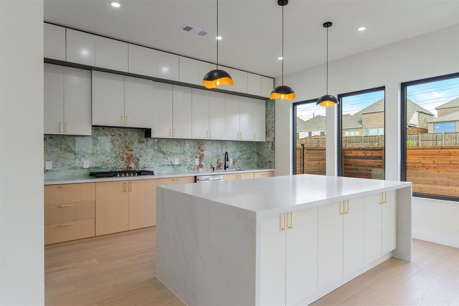 Kitchen with hanging light fixtures, modern cabinets, recessed lighting, light wood-style flooring, and white cabinets