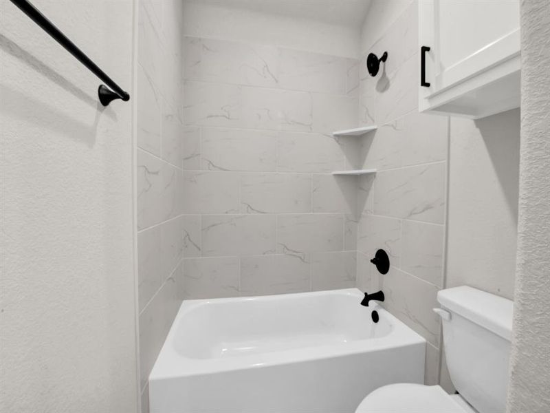 Bathroom with tub / shower combination and a textured wall