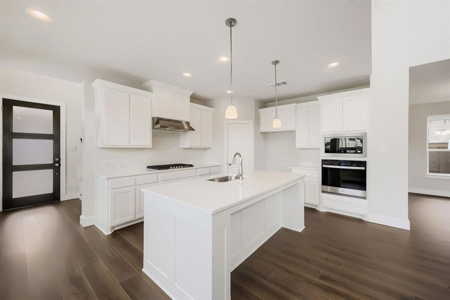 Modern kitchen featuring a large central island with an undermount sink and a gooseneck faucet