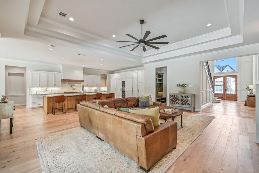 The open-concept family room flows seamlessly into the showpiece island kitchen, with beautiful wood flooring, extensive recessed lighting, an impressive tray ceiling with oversized fan & a clear sightline back to the dramatic 20' foyer.