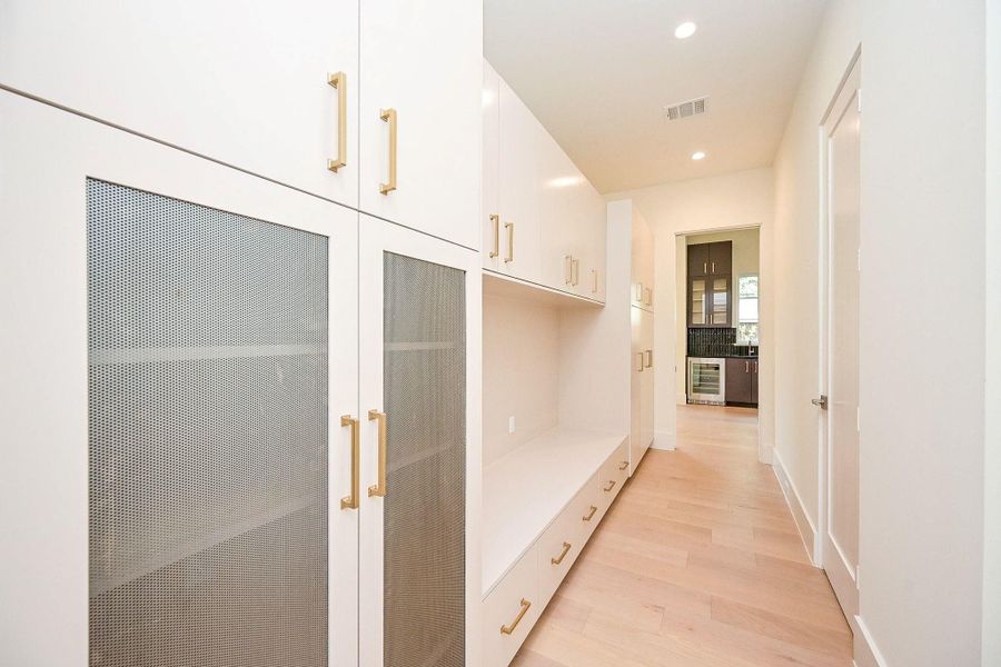 Expansive Mud room with custom Cabinets featuring gold handles and mesh doors.