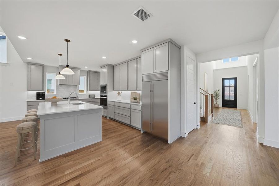 Kitchen featuring gray cabinets, a breakfast bar, light wood-type flooring, and recessed lighting Kitchen featuring gray cabinets, a breakfast bar, light wood-type flooring, and recessed lighting