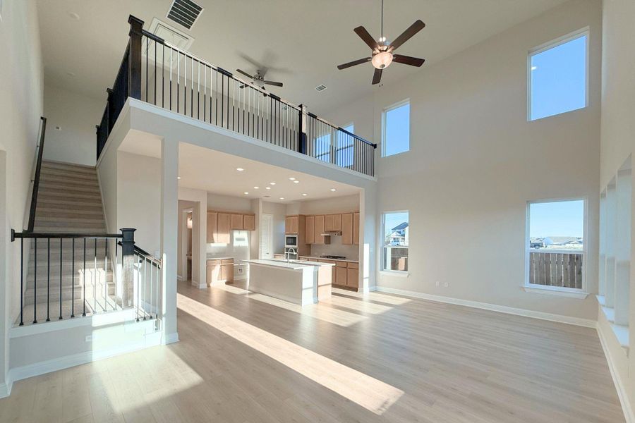 Unfurnished living room featuring a ceiling fan, light wood-style floors, a high ceiling, stairway, and recessed lighting