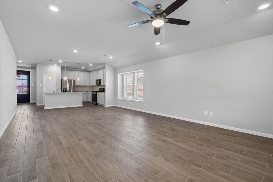 This expansive view from the back of the house showcases a seamless, open-concept layout that creates a warm and inviting path.