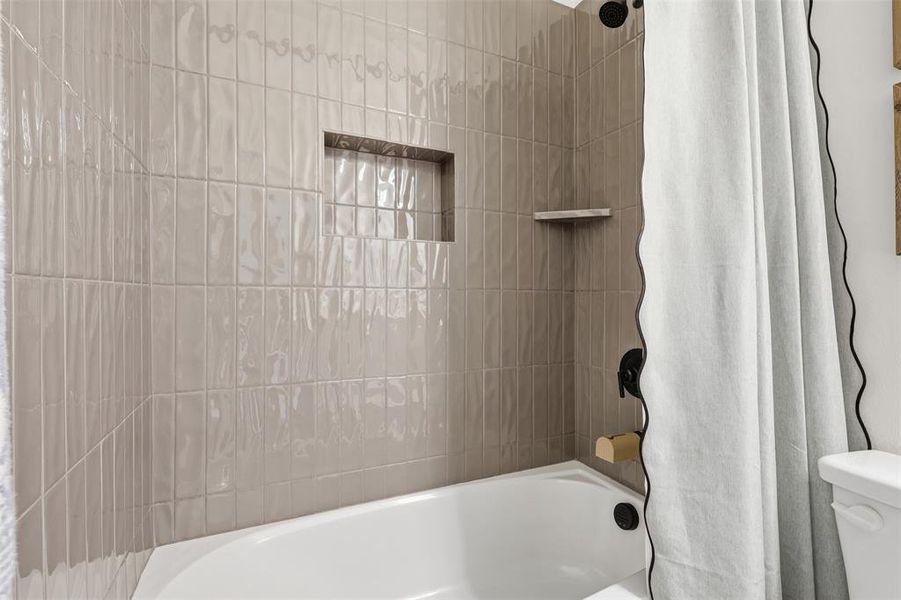 White bathtub with light gray vertical subway tile surround, featuring a built-in shower niche and a corner shelf White bathtub with light gray vertical subway tile surround, featuring a built-in shower niche and a corner shelf