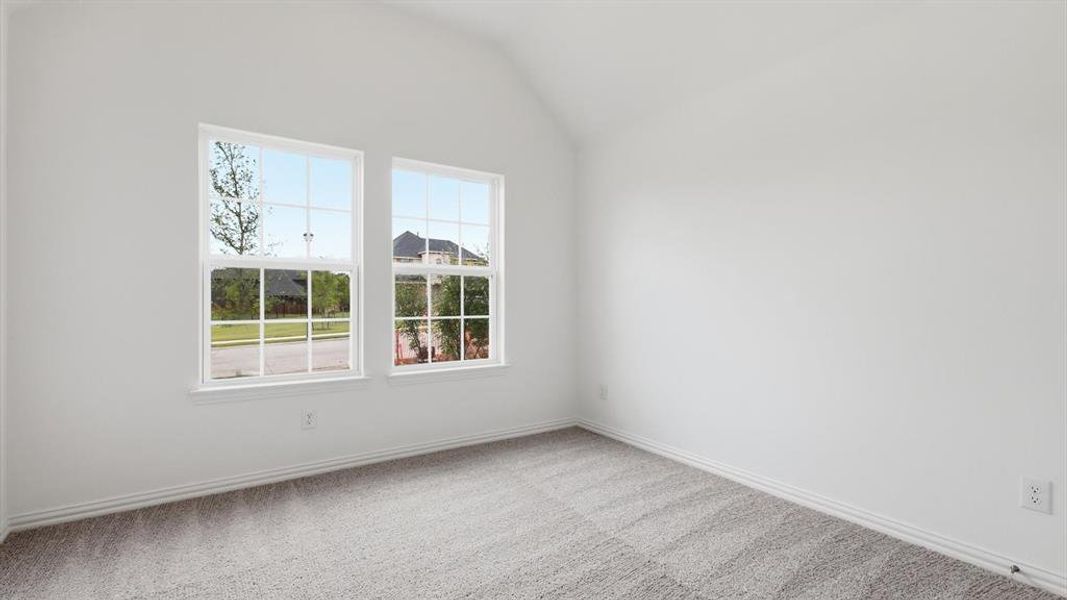 Bright interior room with vaulted ceiling, two prominent double-hung windows, light gray carpet, and white baseboards Bright interior room with vaulted ceiling, two prominent double-hung windows, light gray carpet, and white baseboards