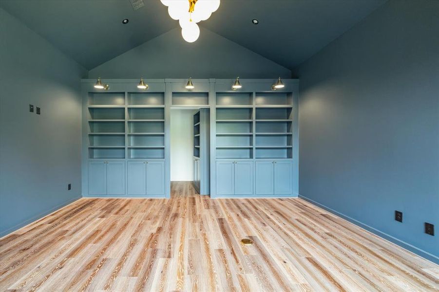 This one of a kind library features a hidden door designed as a built-in bookcase, leading into a secret bonus room. The shelving units are illuminated by stylish sconces, offering both storage and display space. The seamless hidden bookcase adds both functionality and an element of surprise. This clever seamless design element enhances the home's unique appeal while providing a touch of mystery.