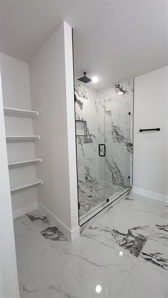Full bath with baseboards, marble finish floor, and a marble finish shower