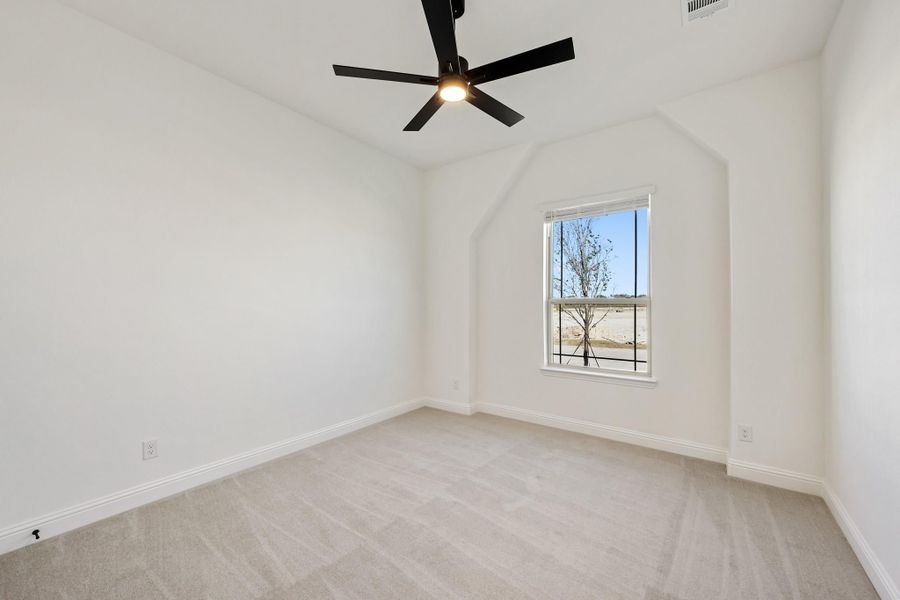Empty bedroom with vaulted ceiling, black ceiling fan, carpet flooring, and single window Empty bedroom with vaulted ceiling, black ceiling fan, carpet flooring, and single window