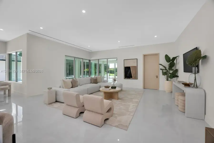 Spacious interior featuring large-format tile flooring, recessed lighting, expansive glass windows, and minimalist trim-less door frames