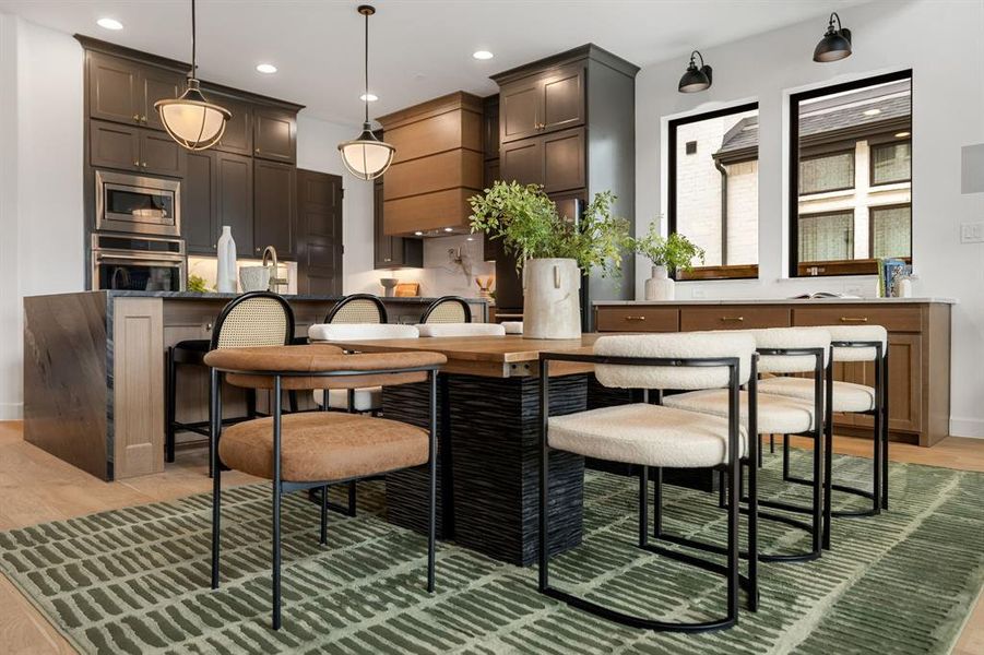Kitchen featuring hanging light fixtures, a kitchen breakfast bar, stainless steel appliances, dark stone countertops, and recessed lighting Kitchen featuring hanging light fixtures, a kitchen breakfast bar, stainless steel appliances, dark stone countertops, and recessed lighting
