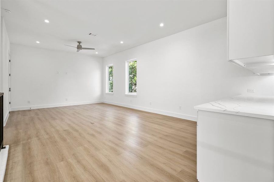 Unfurnished living room with ceiling fan and light wood-type flooring