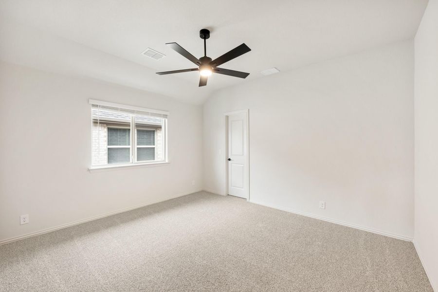 Empty bedroom with vaulted ceiling, black ceiling fan, carpet flooring, and a single window Empty bedroom with vaulted ceiling, black ceiling fan, carpet flooring, and a single window