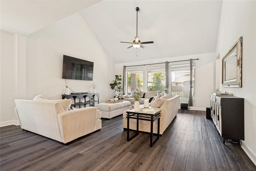 Vaulted ceilings enhance this living space featuring wood-finish flooring, recessed lighting, and a ceiling fan