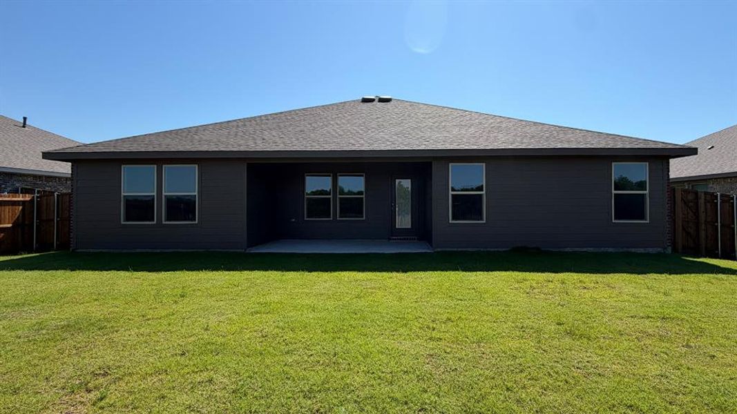 Expansive lawn featuring a concrete patio, dark gray siding, multiple windows, and a shingled roof Expansive lawn featuring a concrete patio, dark gray siding, multiple windows, and a shingled roof