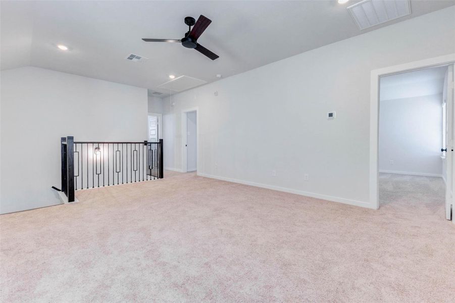 The upstairs game room offers endless flexibility whether it’s a second living room, home office, media space, or play area. Plush carpeting, a stylish ceiling fan, and black iron railing provide a perfect balance of comfort and sophistication.