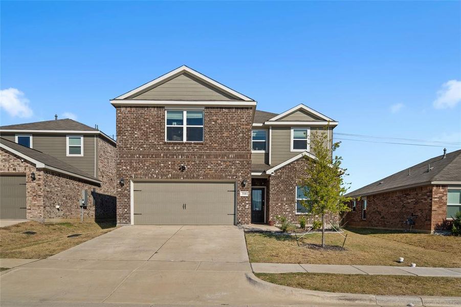 View of front of house with driveway, a front yard, brick siding, and a garage