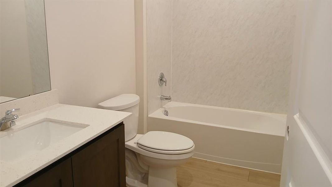 Bathroom featuring a white bathtub, toilet, and vanity with a light-colored countertop Bathroom featuring a white bathtub, toilet, and vanity with a light-colored countertop